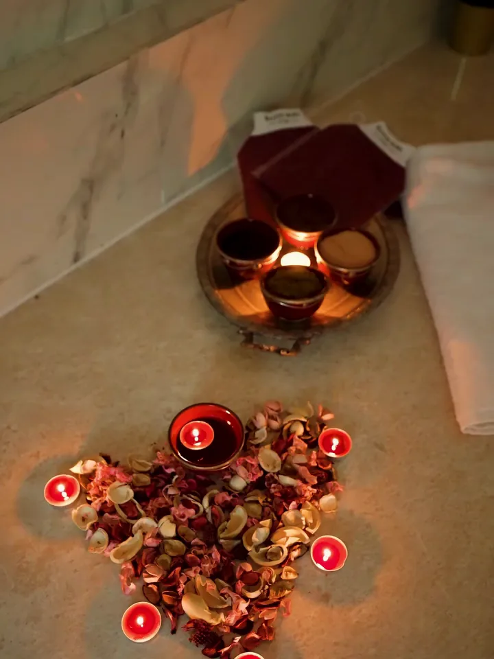 Bougies et pétales de rose posés sur le marbre du hammam