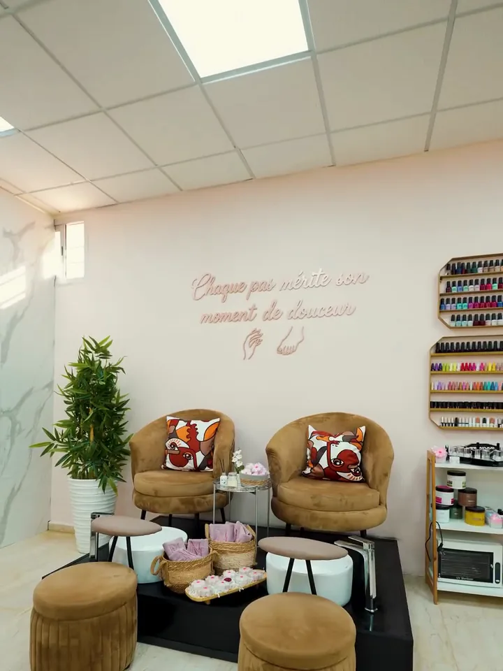 Fauteuils de pédicure et poufs devant le mur de vernis