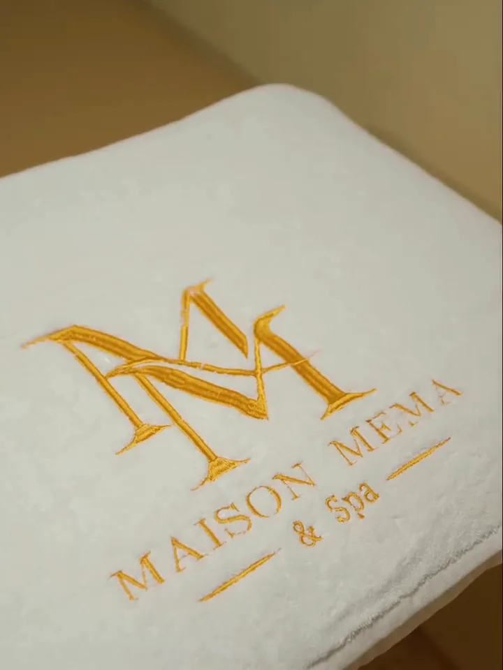 Serviette blanche brodée du logo Maison MeMa en fil doré