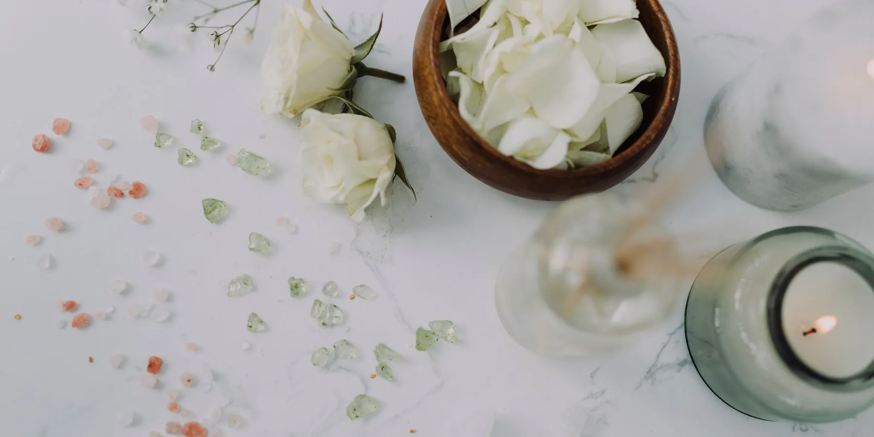 Roses blanches, pétales et bougie sur un plateau de marbre